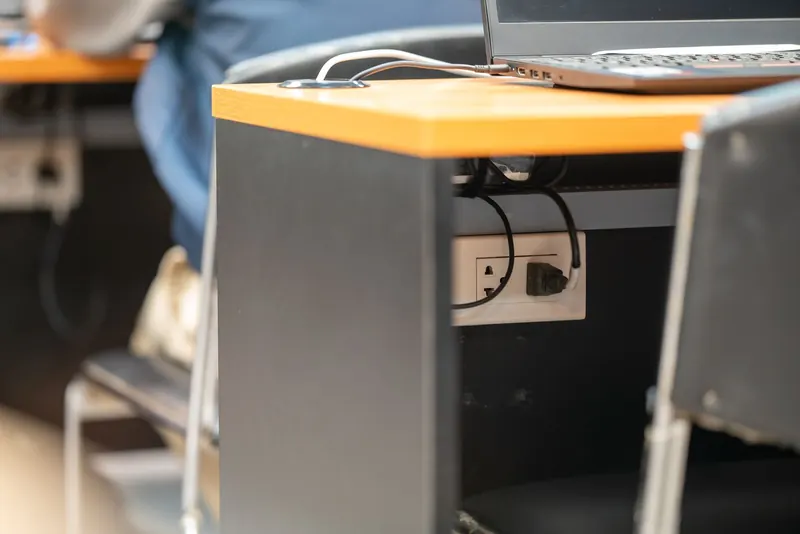 A clean office workspace featuring a desk, laptop, and hidden power cord management