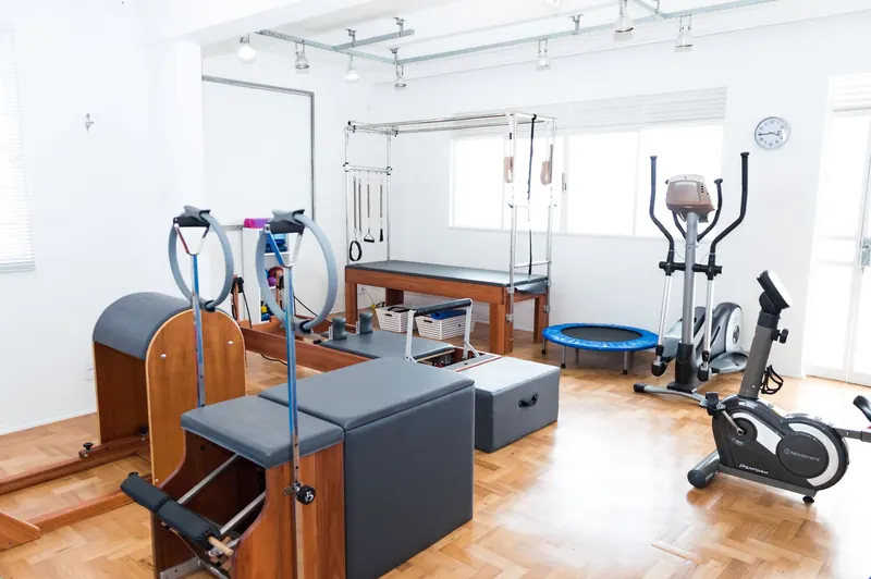 Bright gym space featuring Pilates equipment, exercise bikes, and wooden flooring for a modern workout experience