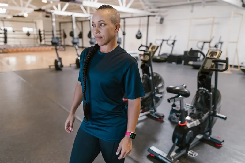 Focused woman in gym preparing for her workout surrounded by exercise equipment